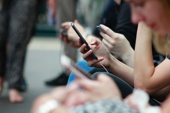 A row of sitting people with smartphones in their hands