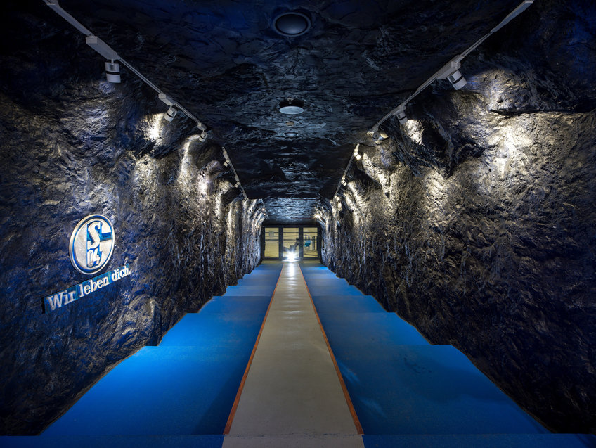 The FC Schalke 04 players' tunnel has black irregularly shaped walls like an adit in a coal mine.