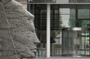 a side-face stone sculpture of Minerva (roughly five meters high) on the left side of the glass entrance of an office building