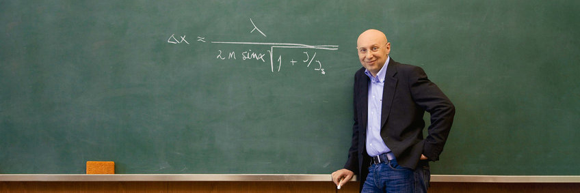 Stefan Hell stands in front of a blackboard. On the board he has scribbled the formula for which he was awarded the Nobel Prize in Chemistry in 2014.