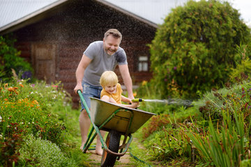 Father plays with his child in a garden. 