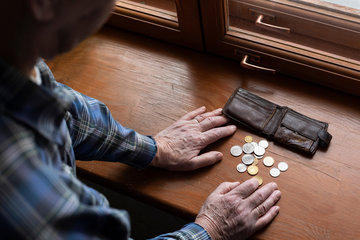 Ältere Person betrachtet die letzten Münzen aus ihrer Brieftasche