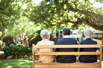 three older people sitting on a bench